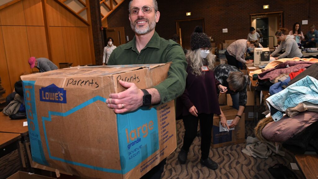 Dan Leshem, director of the Jewish Colorado’s Jewish Community Relations Council, carries a box of donated clothes at Temple Emanuel on Jan. 5, 2023.