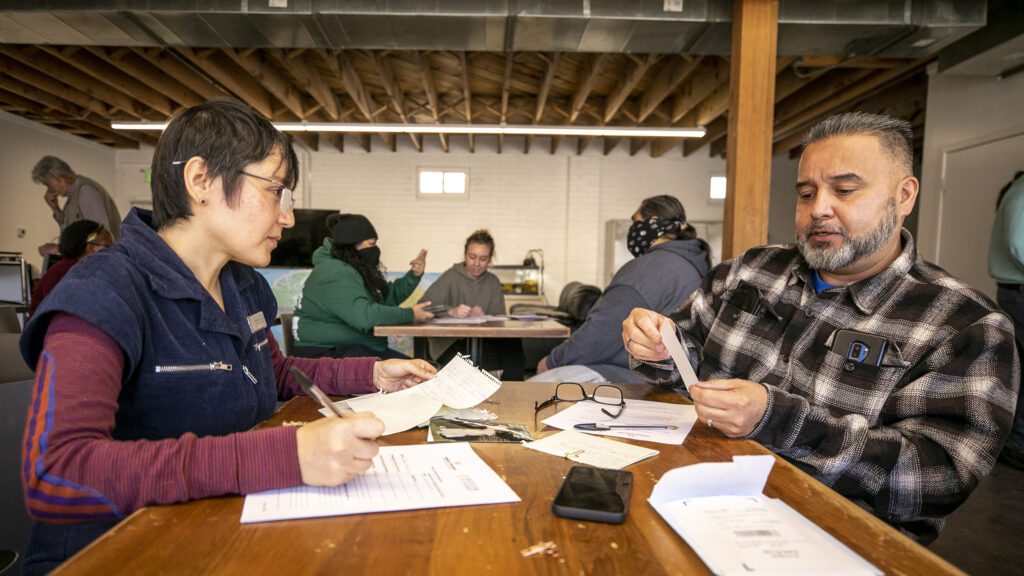 Maria Islas Lopez (left), manager of History Colorado's Museum of Memory project, sorts through Jesse Garcia's photos of Sun Valley. Feb. 25, 2023.