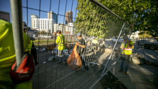 David Sjoberg cleans up his tent as contractors with Environmental Hazmat Services set up fences around him, part of the first encampment sweep of Mayor Mike Johnston's tenure. Aug. 4, 2023.