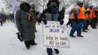 An attendee holds a poster at City Park before the annual Martin Luther King Jr. Day Marade. Jan. 15, 2024.