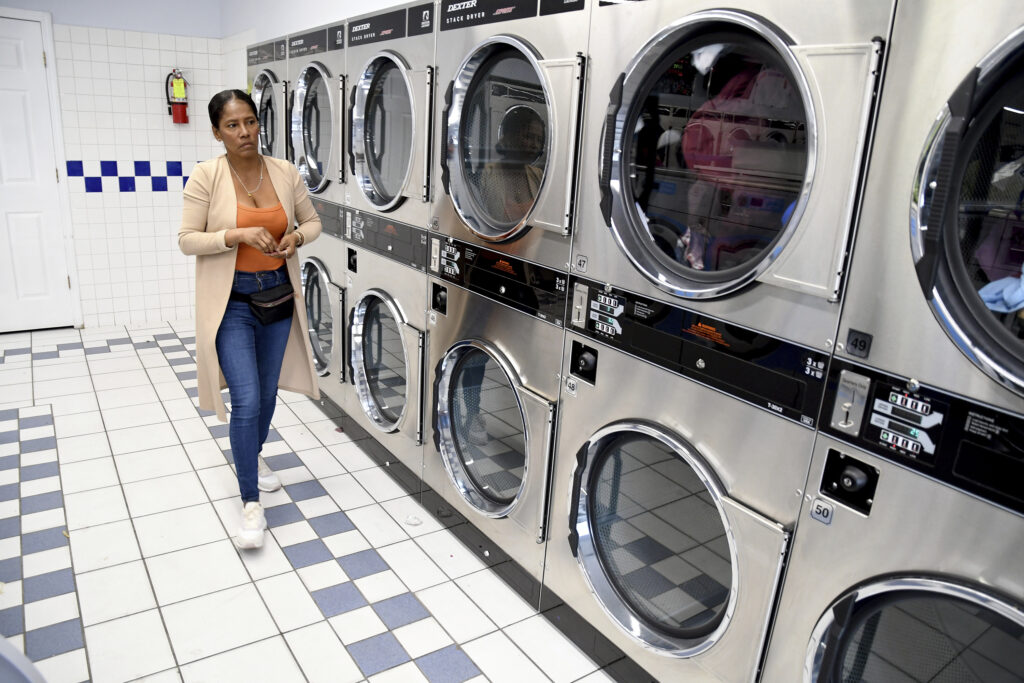 Sofia Roca walks by a line of washing machines at a laundromat.