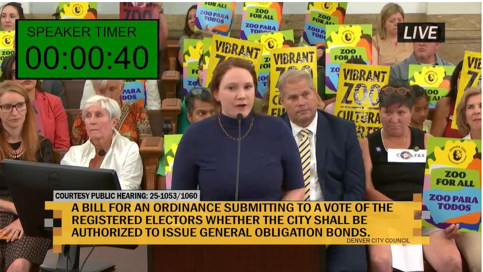 Residents hold Vibrant Zoo signs as they watch a